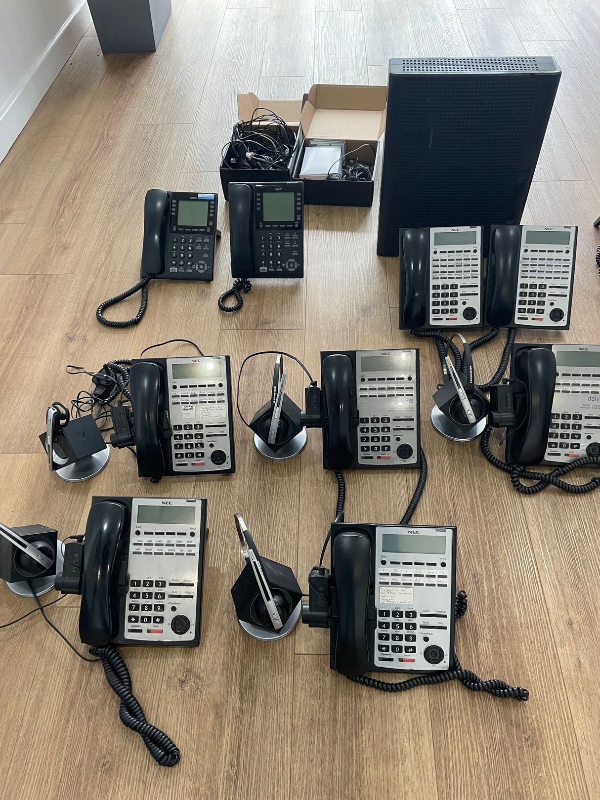 Multiple office telephones arranged on a wooden floor.