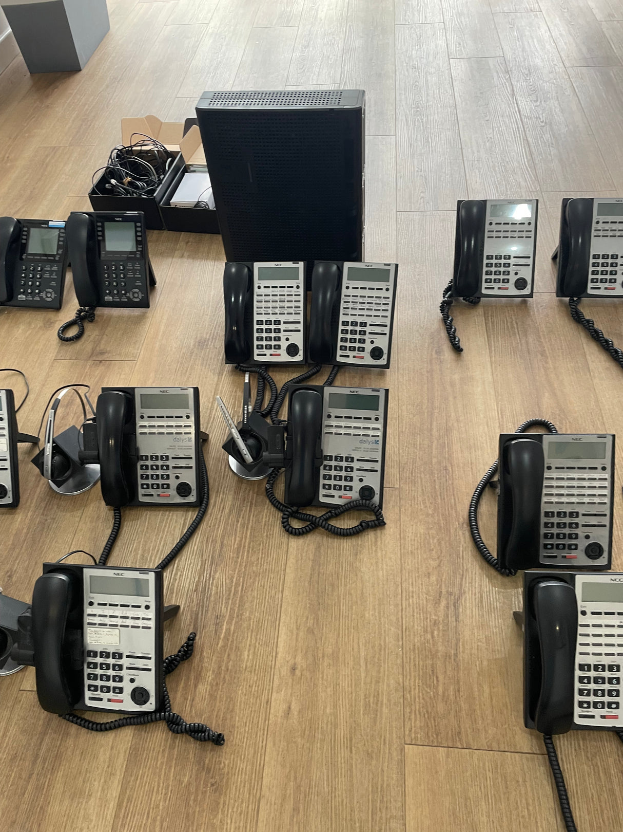 Multiple office phones arranged on a wooden floor.