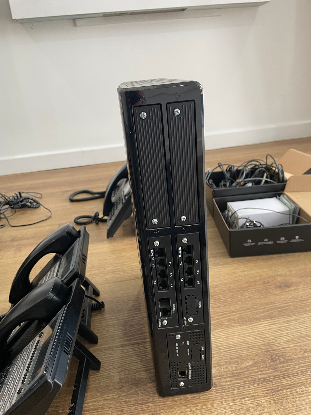 Black electronic device on a wooden desk with office equipment in the background