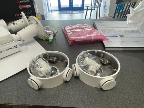 Two white cylindrical devices with clear covers on a gray surface, with Hikmicro branding in the background.