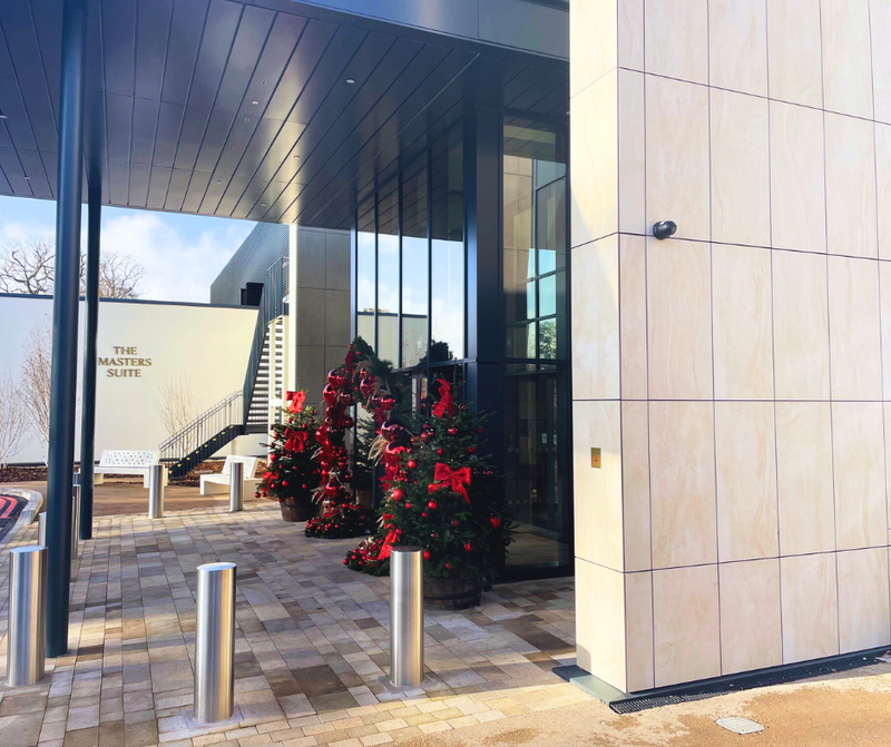 Decorative Christmas trees with red bows outside a modern building entrance with MES Systems black CCTV camera.