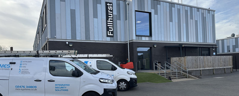 Two white vans MES vans, parked in front of a building with School fitting CCTV