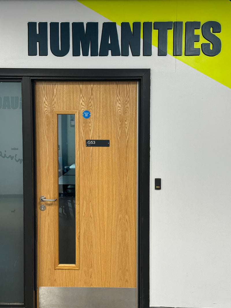 Door with 'Humanities' sign on a bright background and access control.