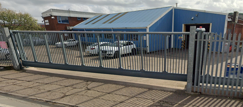Blue industrial building with a metal sliding gate in front