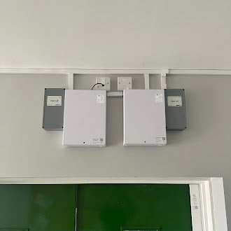 Three access control electrical panels mounted on a wall above a green door.