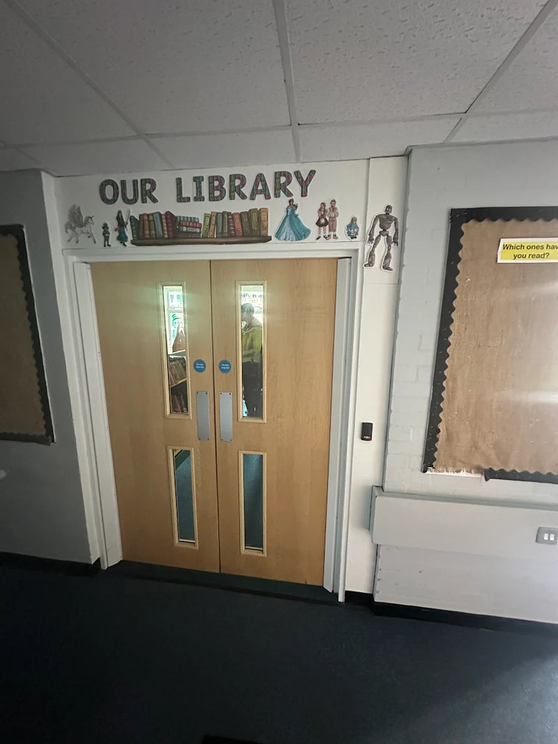 Door to a school library with decorative elements and text 'OUR LIBRARY' on the wall above, and Paxton Net 2 access control.
